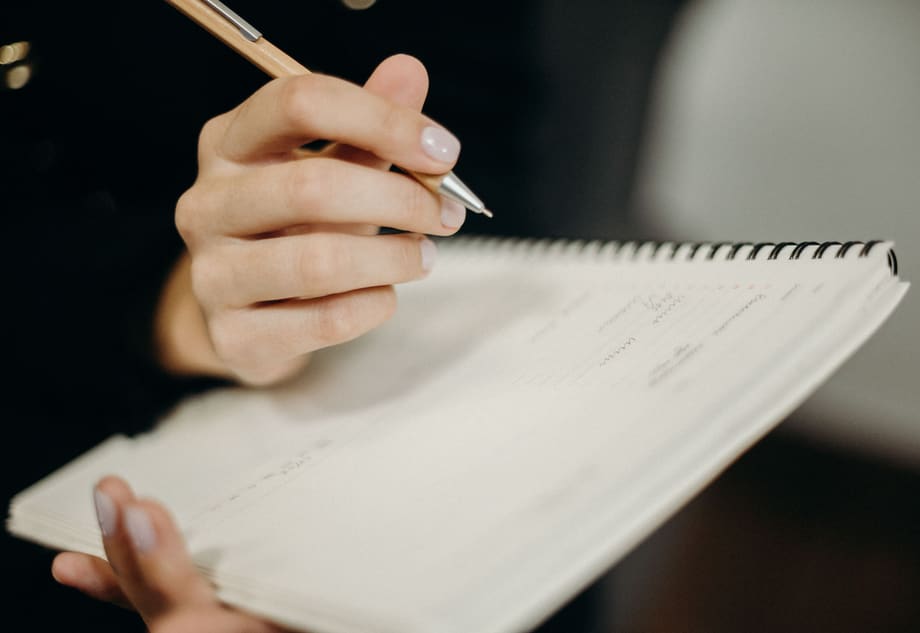 Hands writing a personalised session plan in a notebook